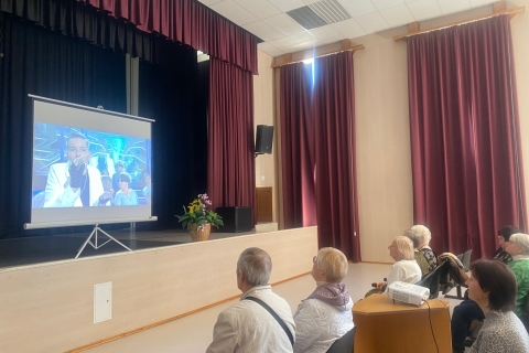 Susirinkusieji stebi Lietuvos aklųjų choro „Feniksas“ vaizdo įrašą